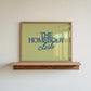 Rectangular landscape digital print with an olive-green background featuring "THE HOMEBODY" in bold blue serif type stacked above "club" in blue cursive script, centered typography layout.