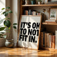 Square cream wall print with bold oversized black chunky typography reading It's Ok To Not Fit In on a clean white background