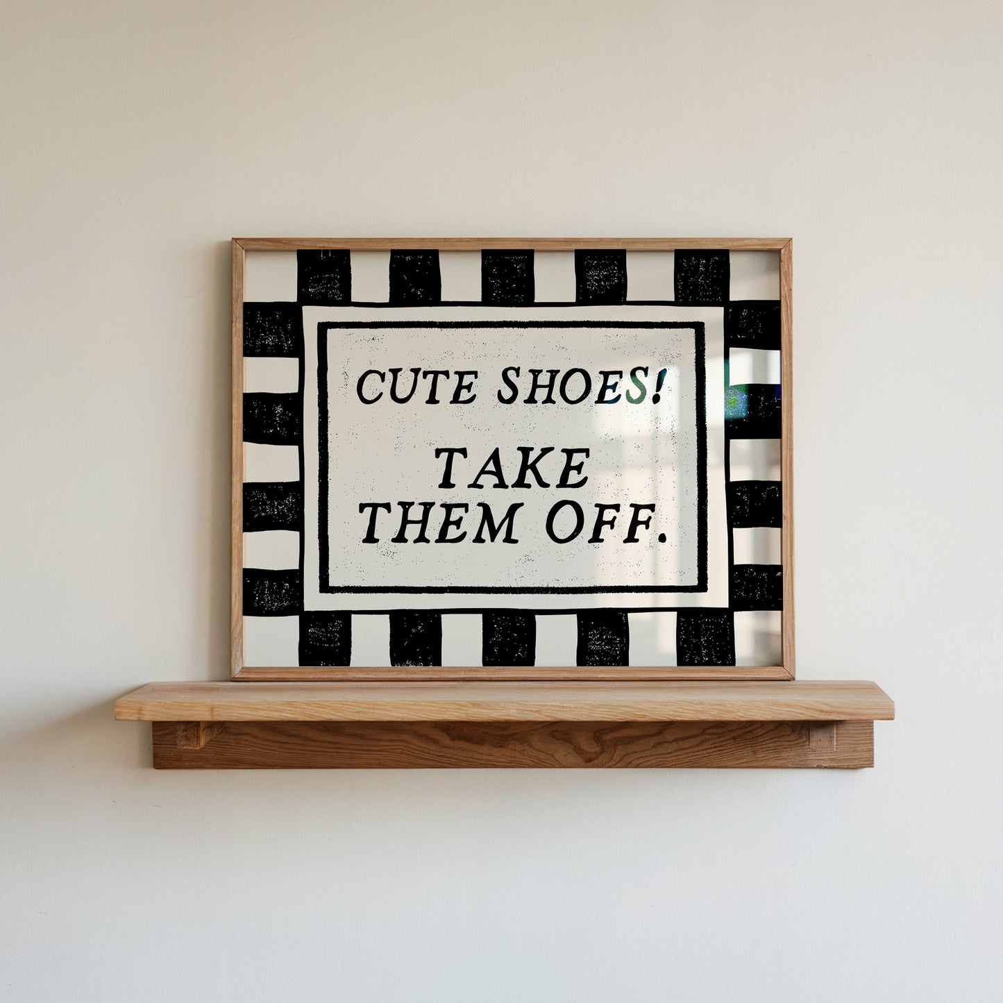 Horizontal print with a bold black and white checkered border framing the quote "CUTE SHOES! TAKE THEM OFF." in black vintage serif type on a cream background.