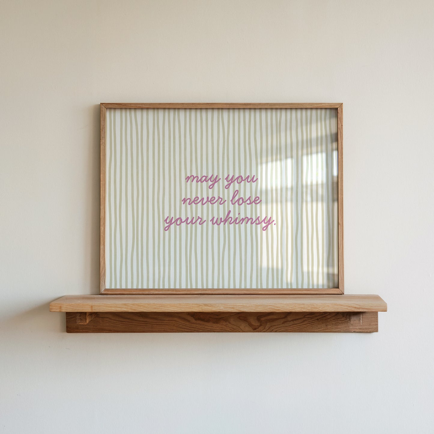 Horizontal wall print with soft sage green wavy vertical stripes and delicate pink cursive script reading may you never lose your whimsy on a warm cream background