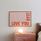 Horizontal wall print with soft pink wavy vertical stripes and bold red rounded typography reading LOVE YOU BYE! in the bottom corner