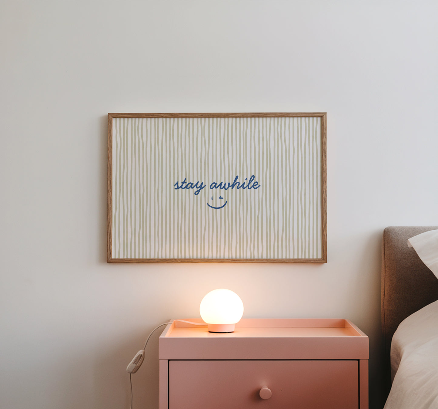 Horizontal print with thin hand-painted tan and cream vertical stripes, the quote "stay awhile" in navy cursive script, and a small hand-drawn smiley face beneath it.