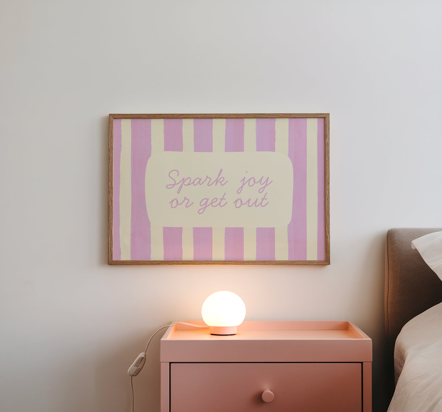 Horizontal art print with hand-painted pink and cream vertical stripes and the quote "Spark joy or get out" in pink cursive script inside a rounded cream panel at the centre.