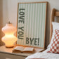 Vertical wall print with soft sage green wavy vertical stripes and bold dark green chunky typography reading LOVE YOU vertically on the left and BYE! horizontally at the bottom right