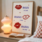 Cream print with three illustrated red lips paired with "Besos," "Bisous," and "Beijos" in navy lettering, with small red hearts scattered throughout