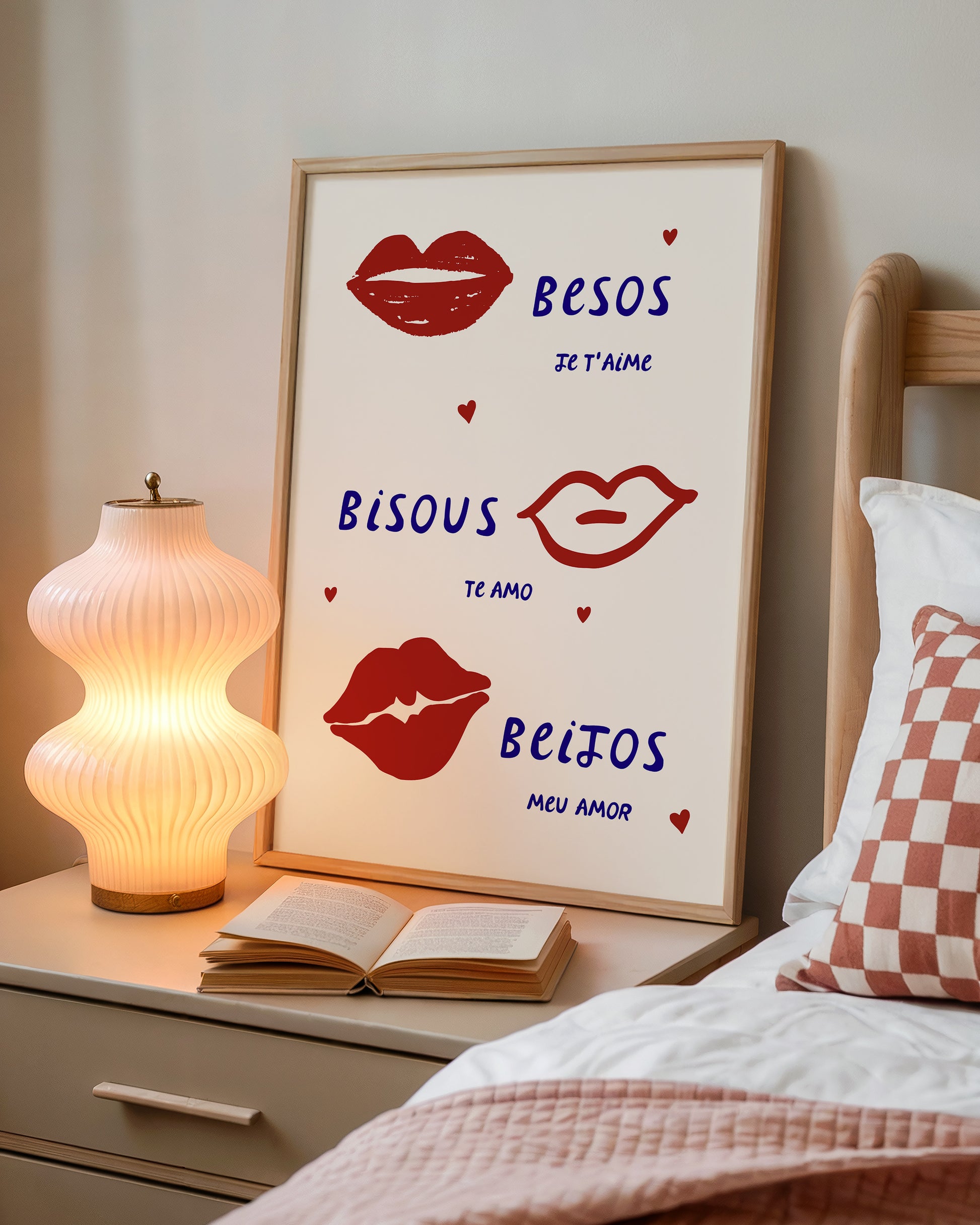 Cream print with three illustrated red lips paired with "Besos," "Bisous," and "Beijos" in navy lettering, with small red hearts scattered throughout