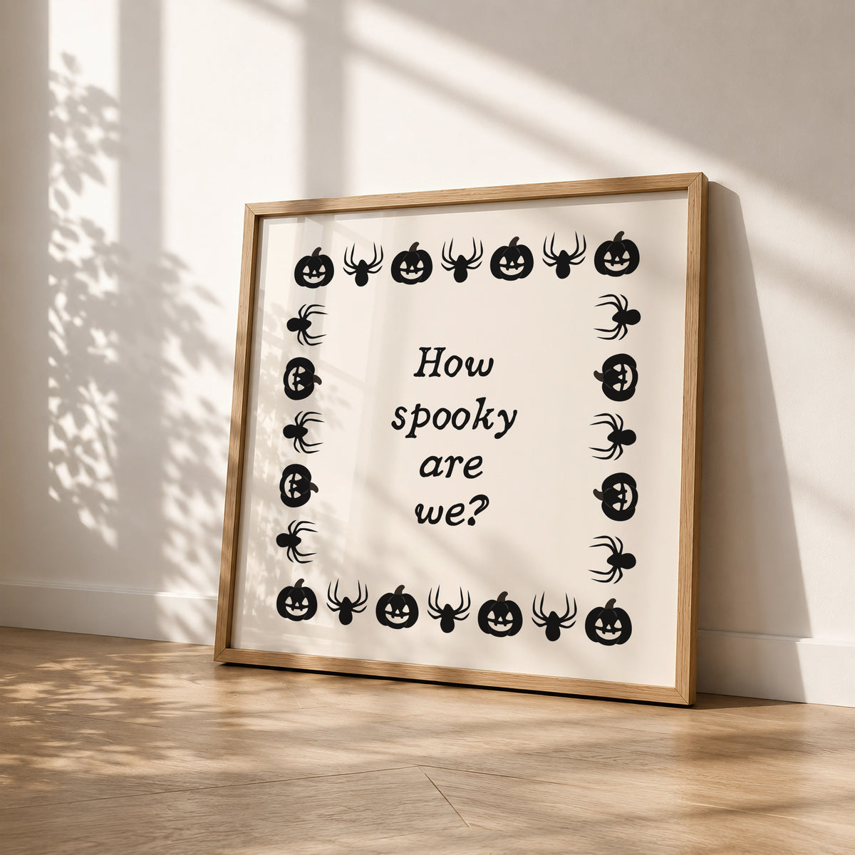 Square digital print with a cream background bordered by alternating black pumpkin and spider illustrations, framing the hand-lettered phrase "How spooky are we?" in black script.