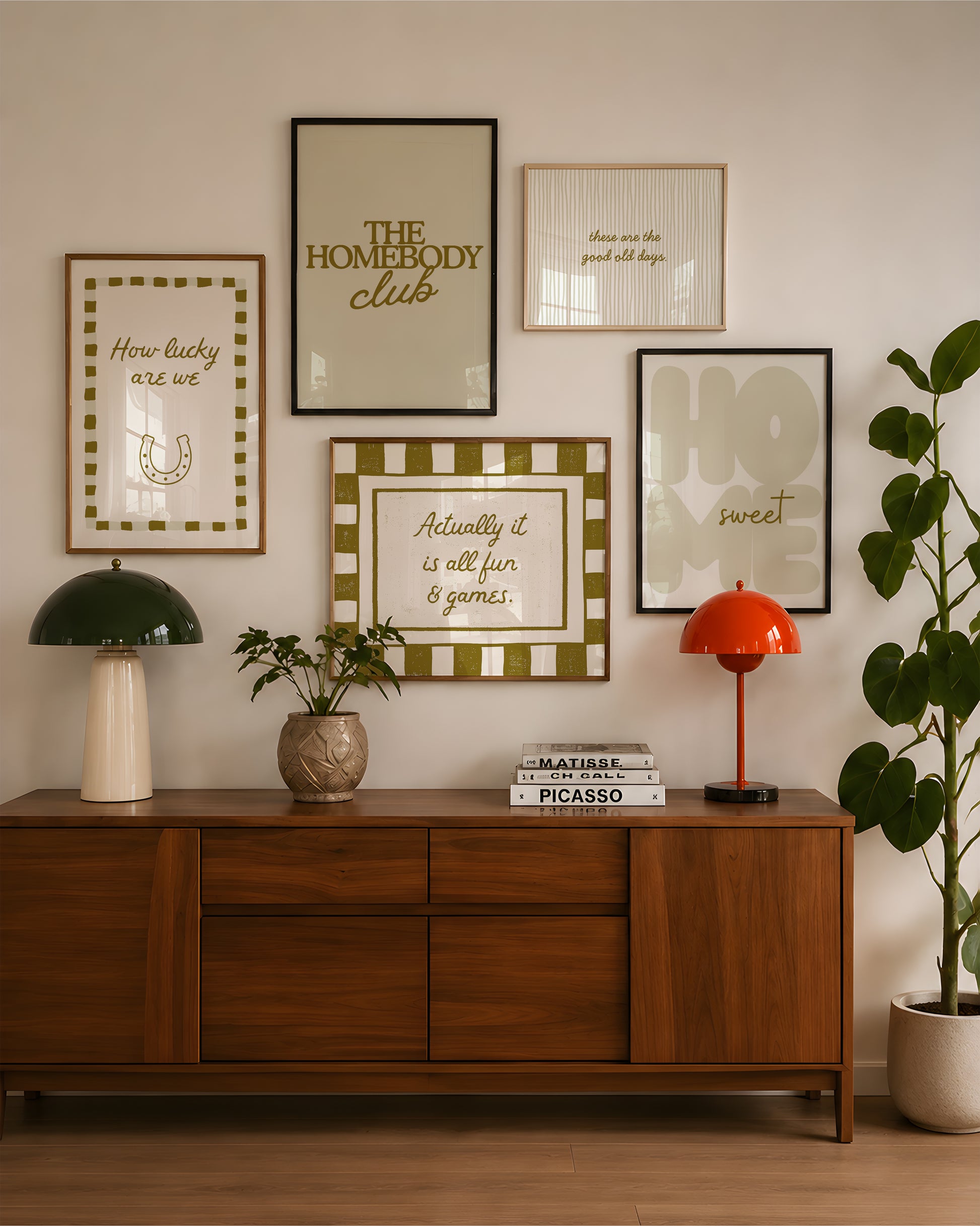 Set of five olive and cream prints including a checkered 'Actually it is all fun & games' print, a horseshoe 'How lucky are we' print, 'The Homebody Club', a striped 'good old days' print, and bubble-letter 'Home sweet'