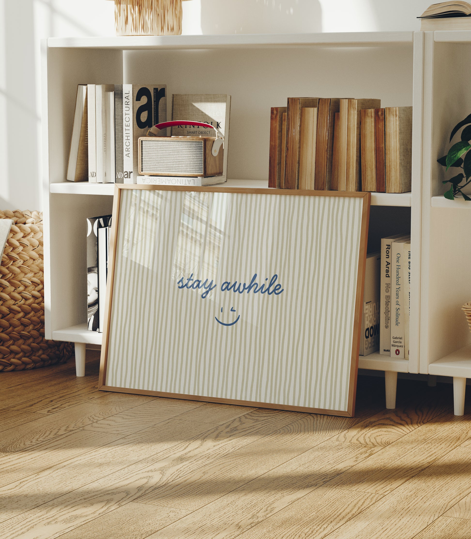 Horizontal print with thin hand-painted tan and cream vertical stripes, the quote "stay awhile" in navy cursive script, and a small hand-drawn smiley face beneath it.