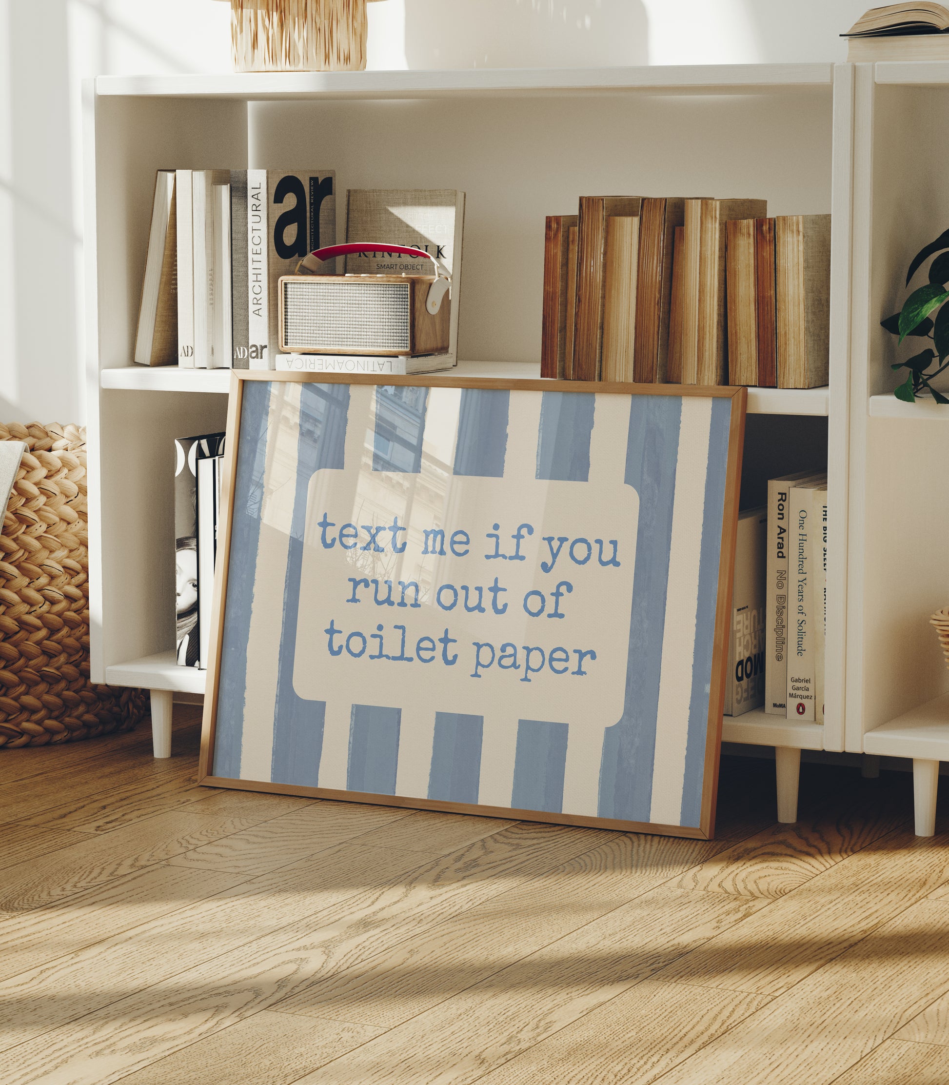 Horizontal wall print with dusty blue vertical brush stripes and a cream rounded text box in retro typewriter font reading text me if you run out of toilet paper