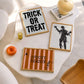 Set of 3 Halloween prints: "Trick or Treat" in dripping black lettering, "Spooky Season" on orange striped fabric with a spider and skeleton, and a bold black silhouette of a mummy.