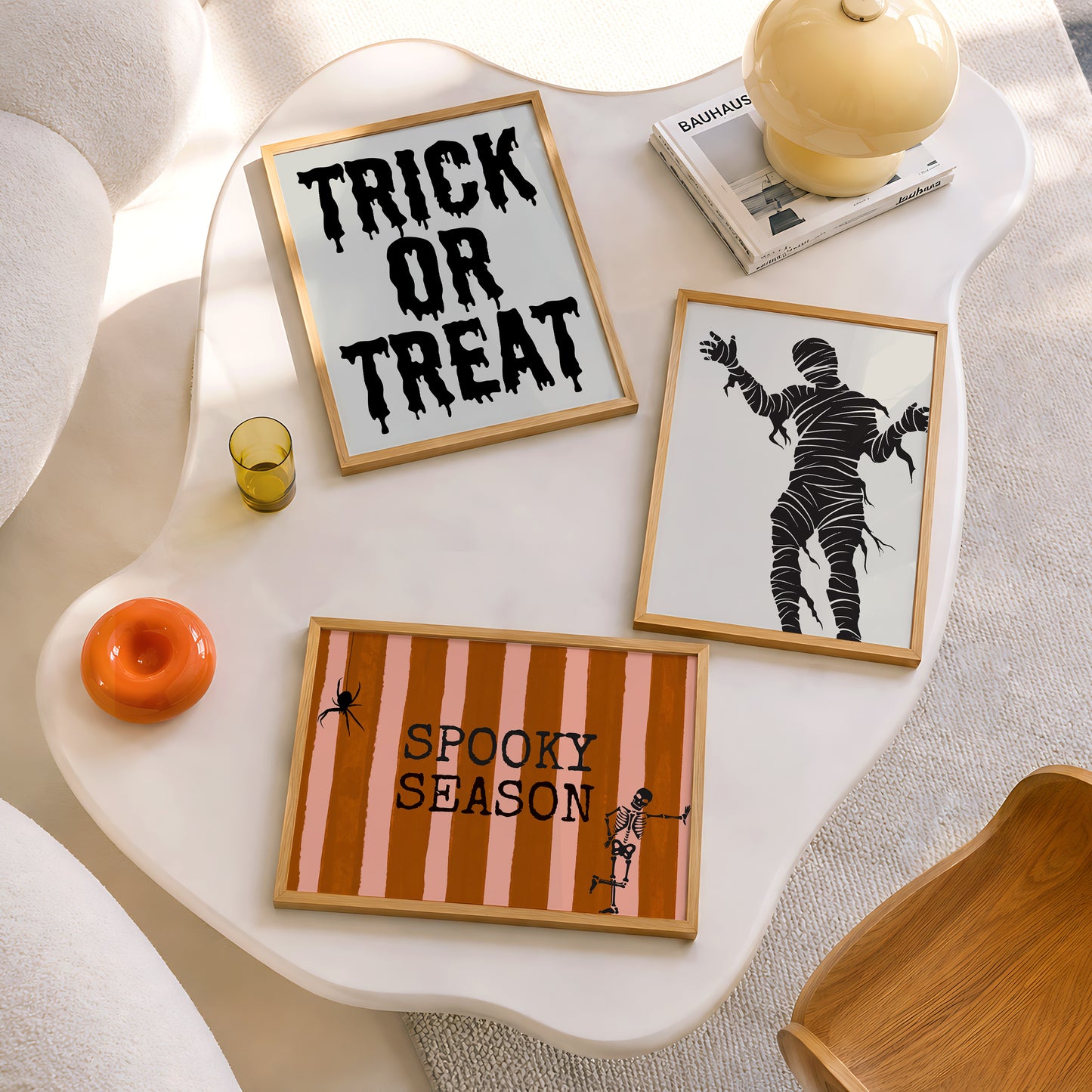 Set of 3 Halloween prints: "Trick or Treat" in dripping black lettering, "Spooky Season" on orange striped fabric with a spider and skeleton, and a bold black silhouette of a mummy.