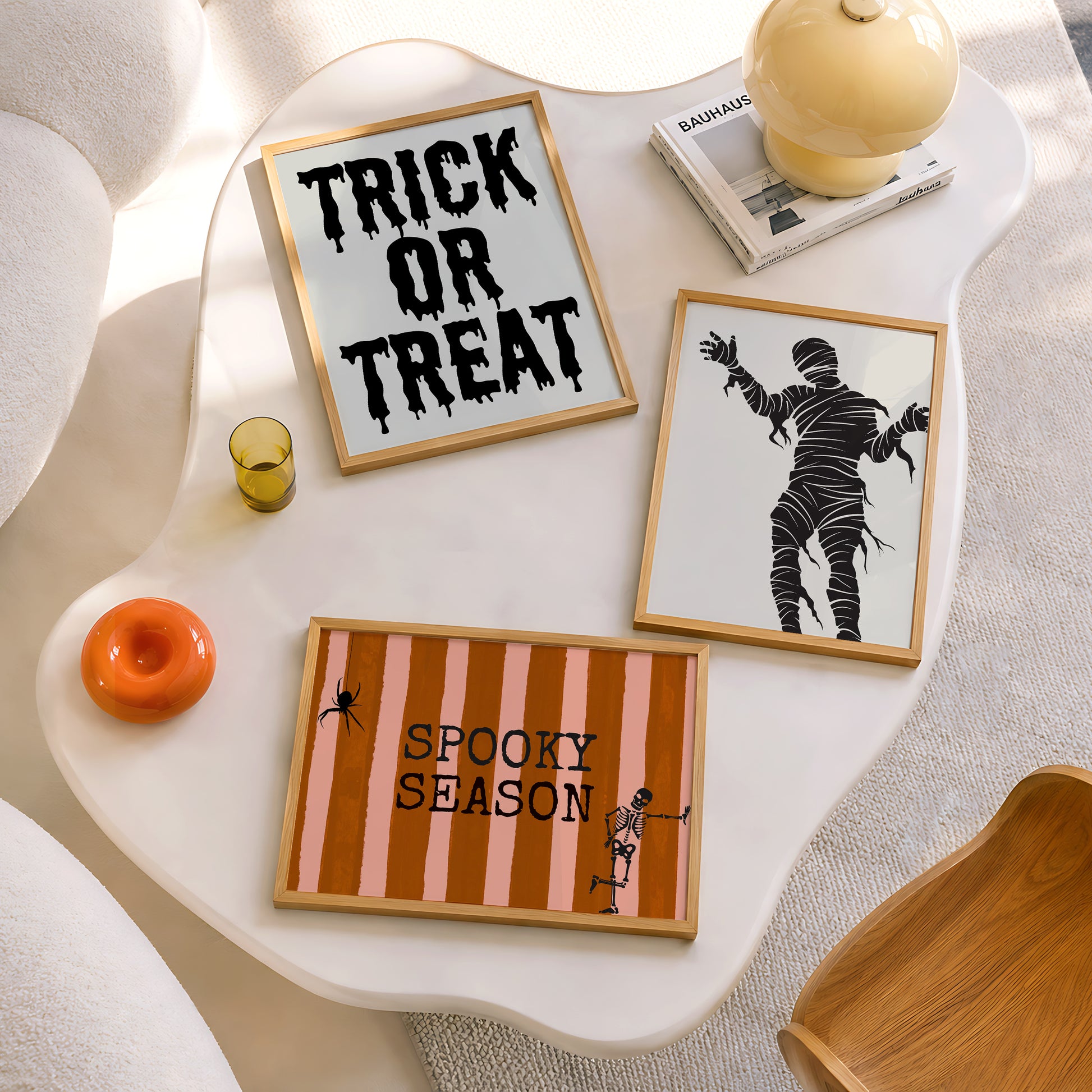 Set of 3 Halloween prints: "Trick or Treat" in dripping black lettering, "Spooky Season" on orange striped fabric with a spider and skeleton, and a bold black silhouette of a mummy.