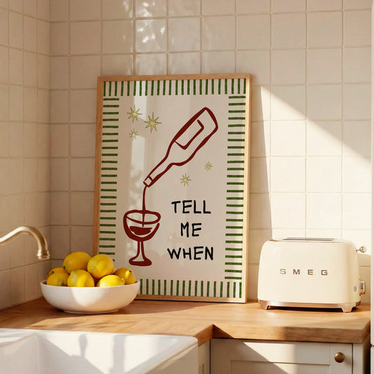 Vertical cream wall print with green stripe border, gold star details, and bold black typography reading Tell Me When alongside dark red hand-drawn line art of a wine bottle pouring into a glass