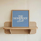 Square digital print with a dusty blue background featuring "THE HOMEBODY" in bold cream serif type stacked above "club" in cream cursive script, centered typography layout.