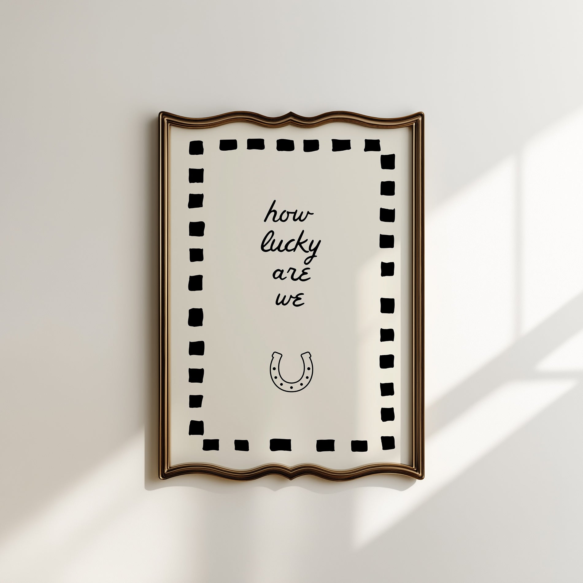 Cream print with a black dashed border featuring the handwritten quote 'how lucky are we' and a horseshoe illustration