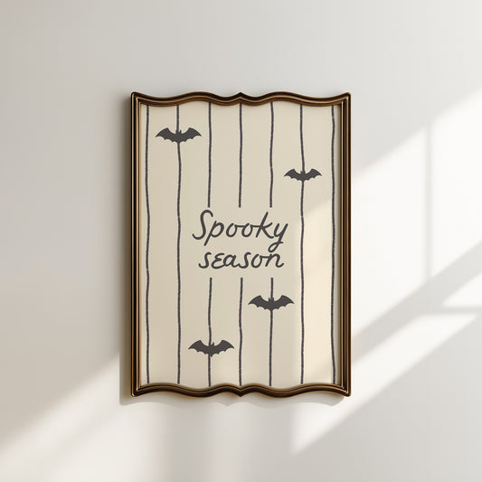 Portrait digital print with a tan and cream striped background featuring the hand-lettered phrase "Spooky season" in black script, accented with three minimalist black bat silhouettes.