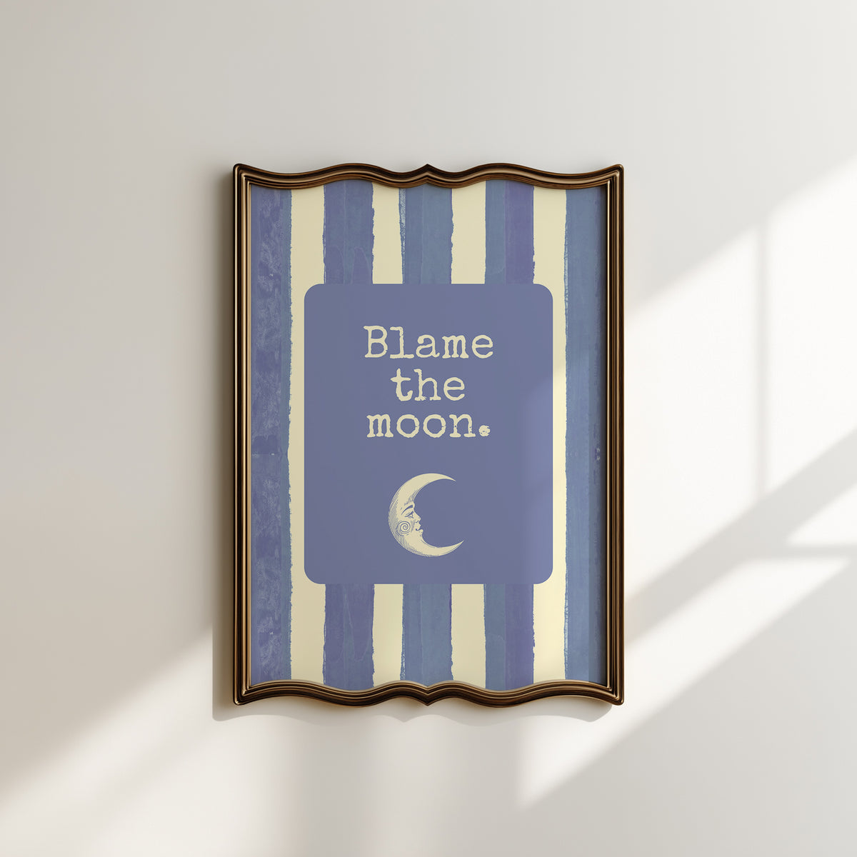 Portrait digital print with blue-and-cream striped background featuring a rounded blue panel with the text "Blame the moon." in cream lettering above a vintage-style crescent moon face illustration.