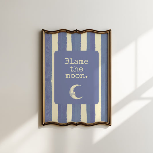 Portrait digital print with blue-and-cream striped background featuring a rounded blue panel with the text "Blame the moon." in cream lettering above a vintage-style crescent moon face illustration.