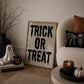 Set of 3 Halloween prints: "Trick or Treat" in dripping black lettering, "Spooky Season" on orange striped fabric with a spider and skeleton, and a bold black silhouette of a mummy.