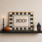 Horizontal print with a bold black and white checkered border framing the word "BOO!" in black hand-drawn type on a textured cream background.
