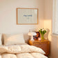 Horizontal print with thin hand-painted tan and cream vertical stripes, the quote "stay awhile" in navy cursive script, and a small hand-drawn smiley face beneath it.