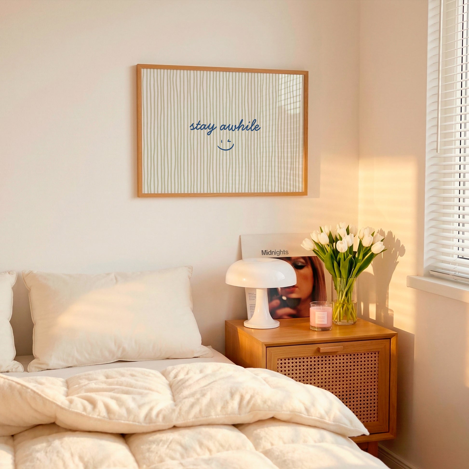 Horizontal print with thin hand-painted tan and cream vertical stripes, the quote "stay awhile" in navy cursive script, and a small hand-drawn smiley face beneath it.