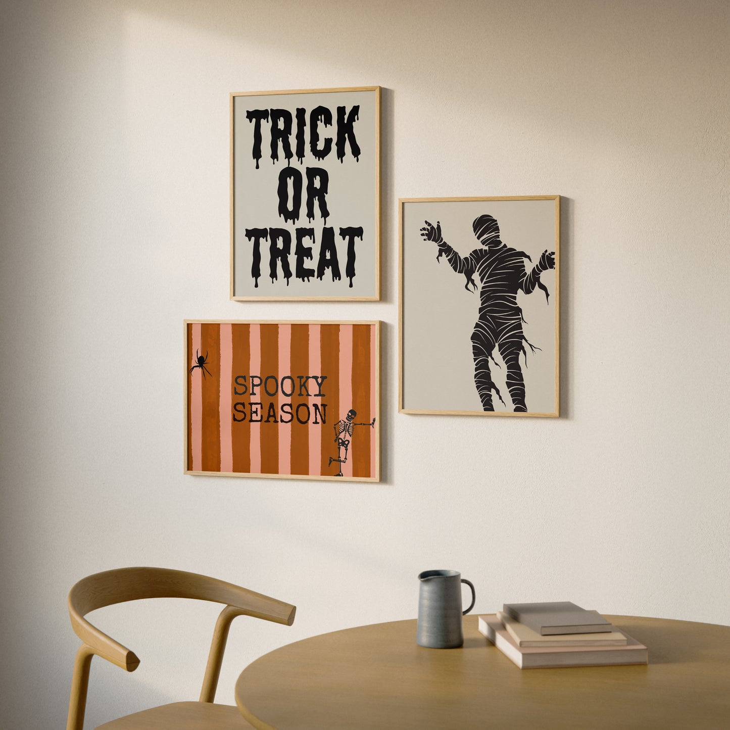 Set of 3 Halloween prints: "Trick or Treat" in dripping black lettering, "Spooky Season" on orange striped fabric with a spider and skeleton, and a bold black silhouette of a mummy.