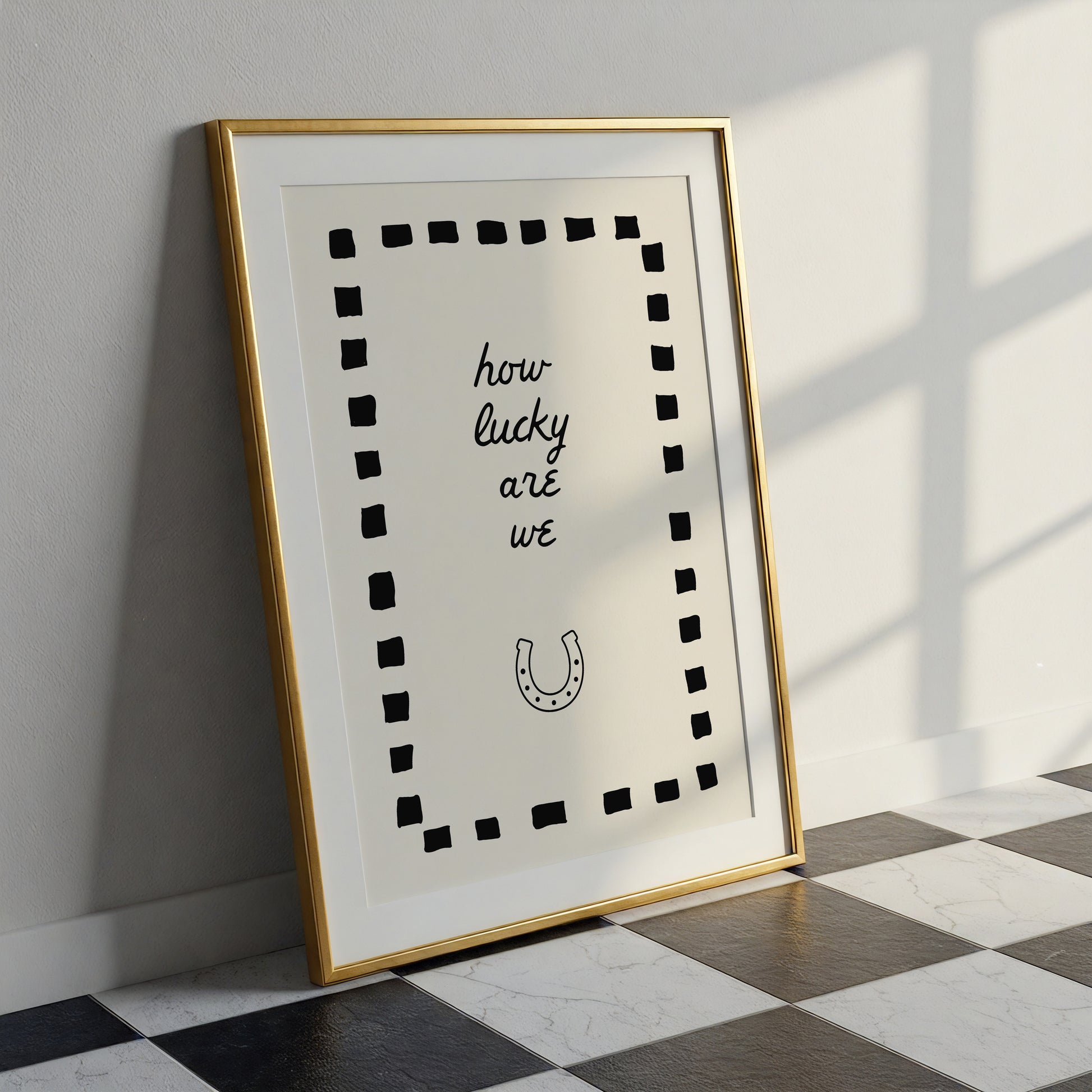 Cream print with a black dashed border featuring the handwritten quote 'how lucky are we' and a horseshoe illustration