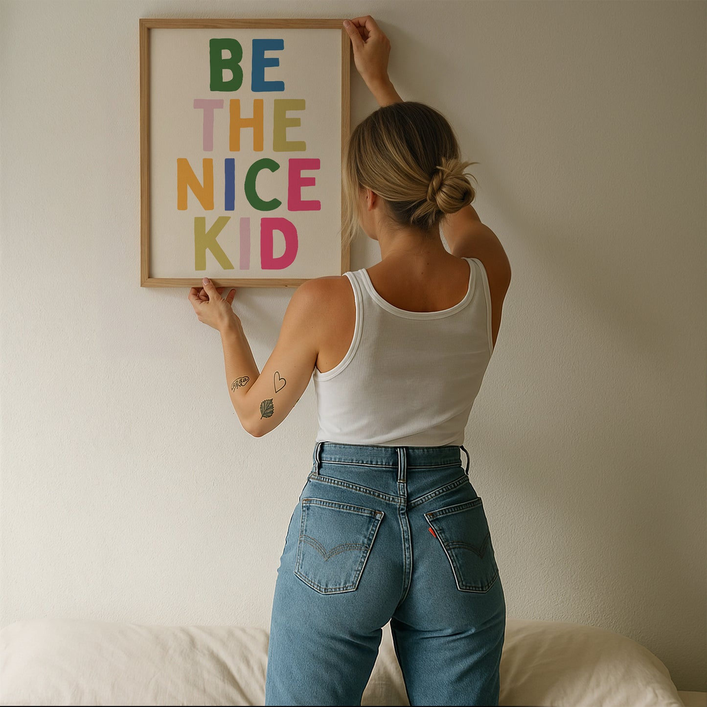 Vertical print with the words "BE THE NICE KID" stacked in large multicolored bubble letters on a cream background in a blue frame.