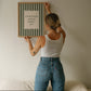 Vertical wall print with bold forest green vertical stripes and a cream scalloped text box reading Everything Always Works Out in dark green serif typography
