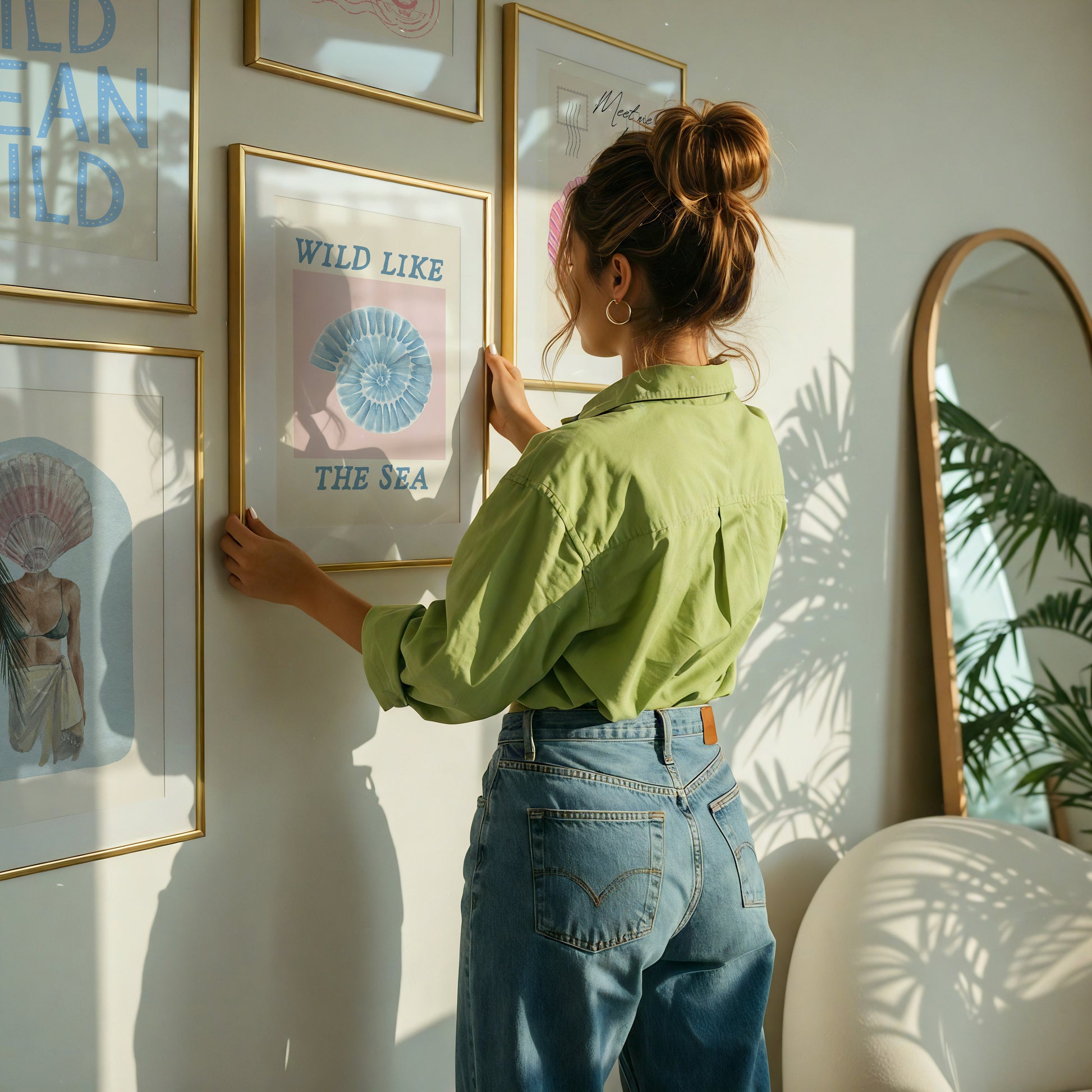 Set of 10 coastal watercolor prints in pink and blue: "Wild Like the Sea" beside a spiral shell illustration, "Stay Wild Ocean Child" in bold blue lettering, "Sea La Vie" in pink stamped typography, a mermaid lounging in a martini glass, pink starfish and seashell illustrations, a woman in a shell headdress, a beach umbrella watercolor, and "Meet me by the sea" in postcard-style script.
