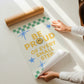 Cream print with a green checkered border, blue stars, and the phrase 'Be Proud of every small step' in yellow lettering with a smiley face replacing the O in Proud
