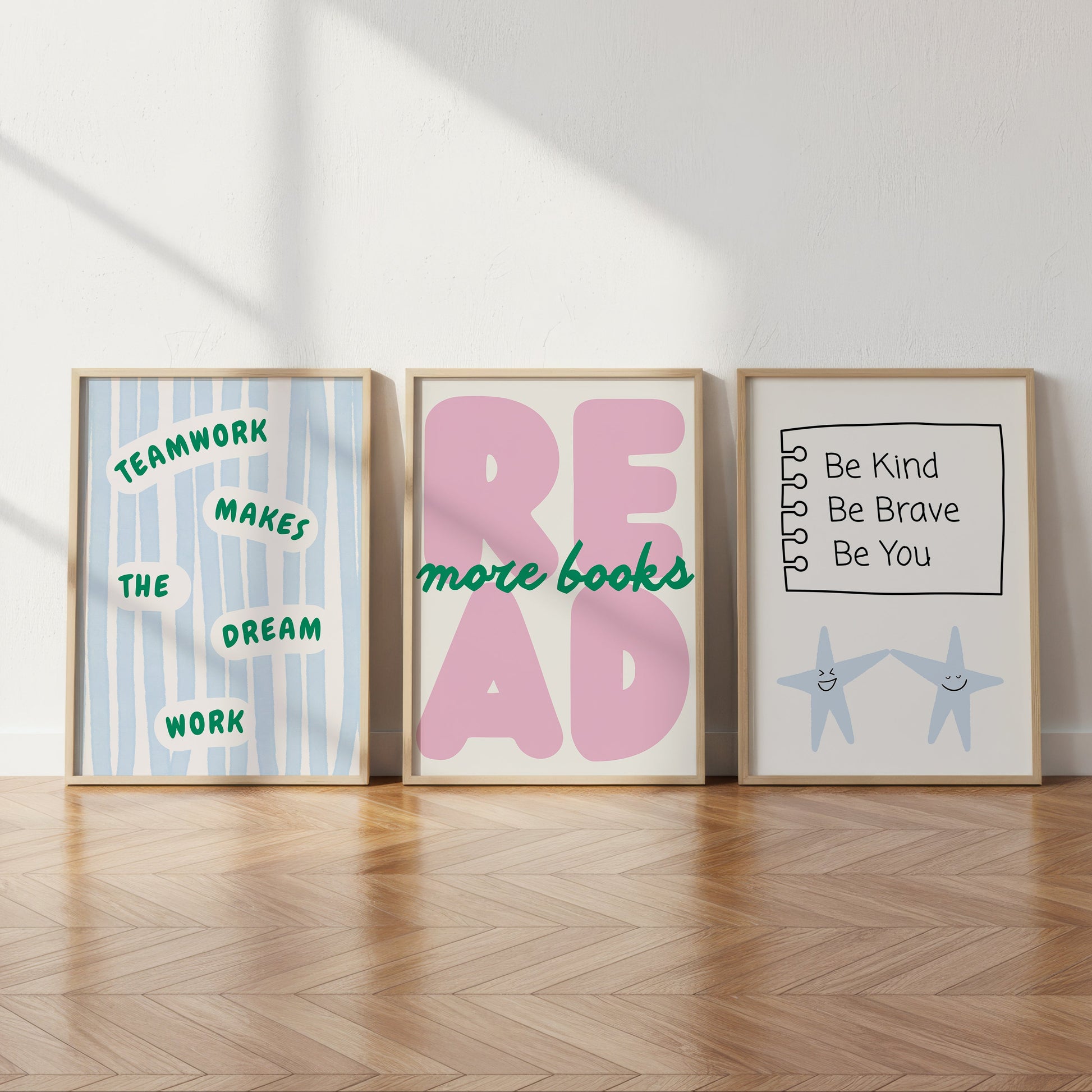 Set of 3 pastel classroom prints: "Teamwork makes the dream work" in green lettering on blue stripes, "READ more books" in pink bubble letters with green script, and "Be Kind Be Brave Be You" on a hand-drawn notebook page above two smiling star characters holding hands.