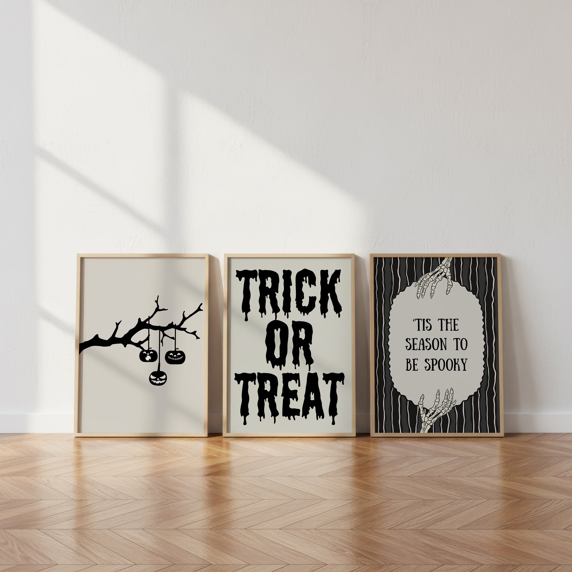 Set of 3 black and white Halloween prints: dripping "Trick or Treat" typography, "'Tis the season to be spooky" framed by skeleton hands, and a black silhouette branch with hanging jack-o'-lanterns.